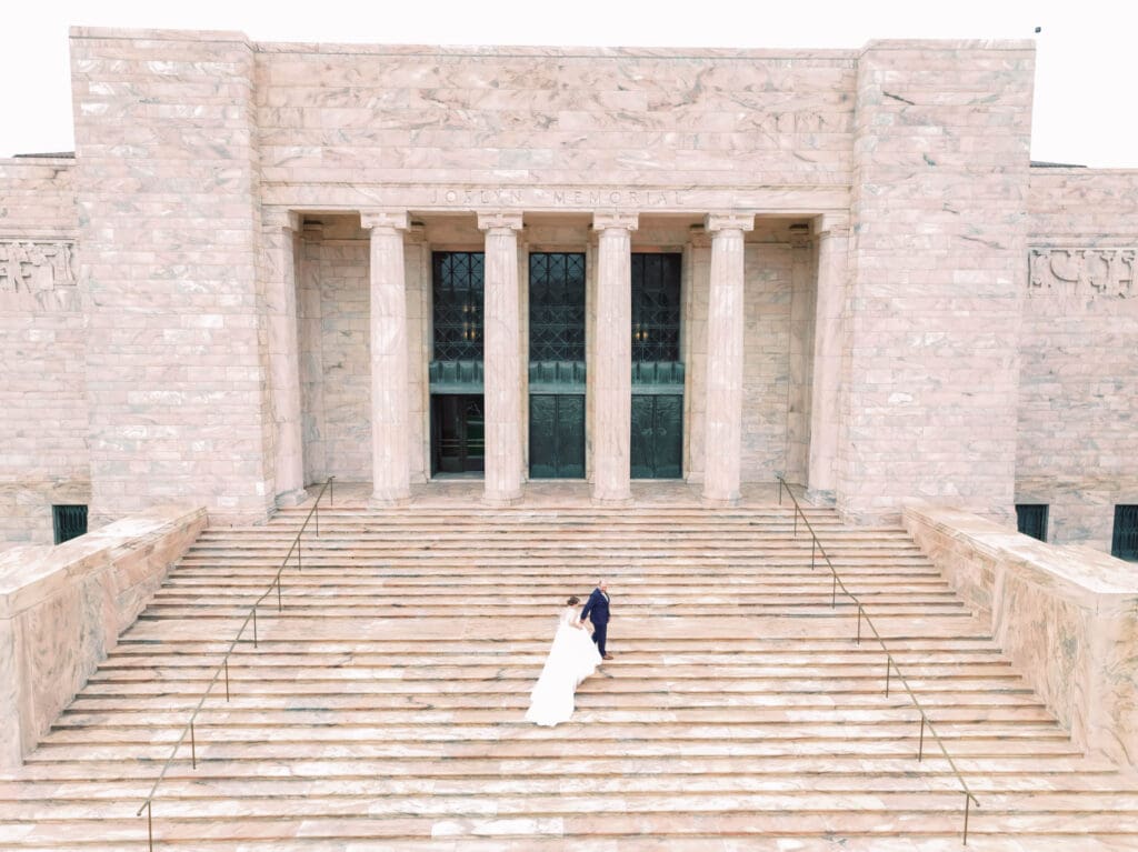 A bride and groom on the steps of the Joslyn Art Museum, one of the best wedding venues in Omaha for 2026