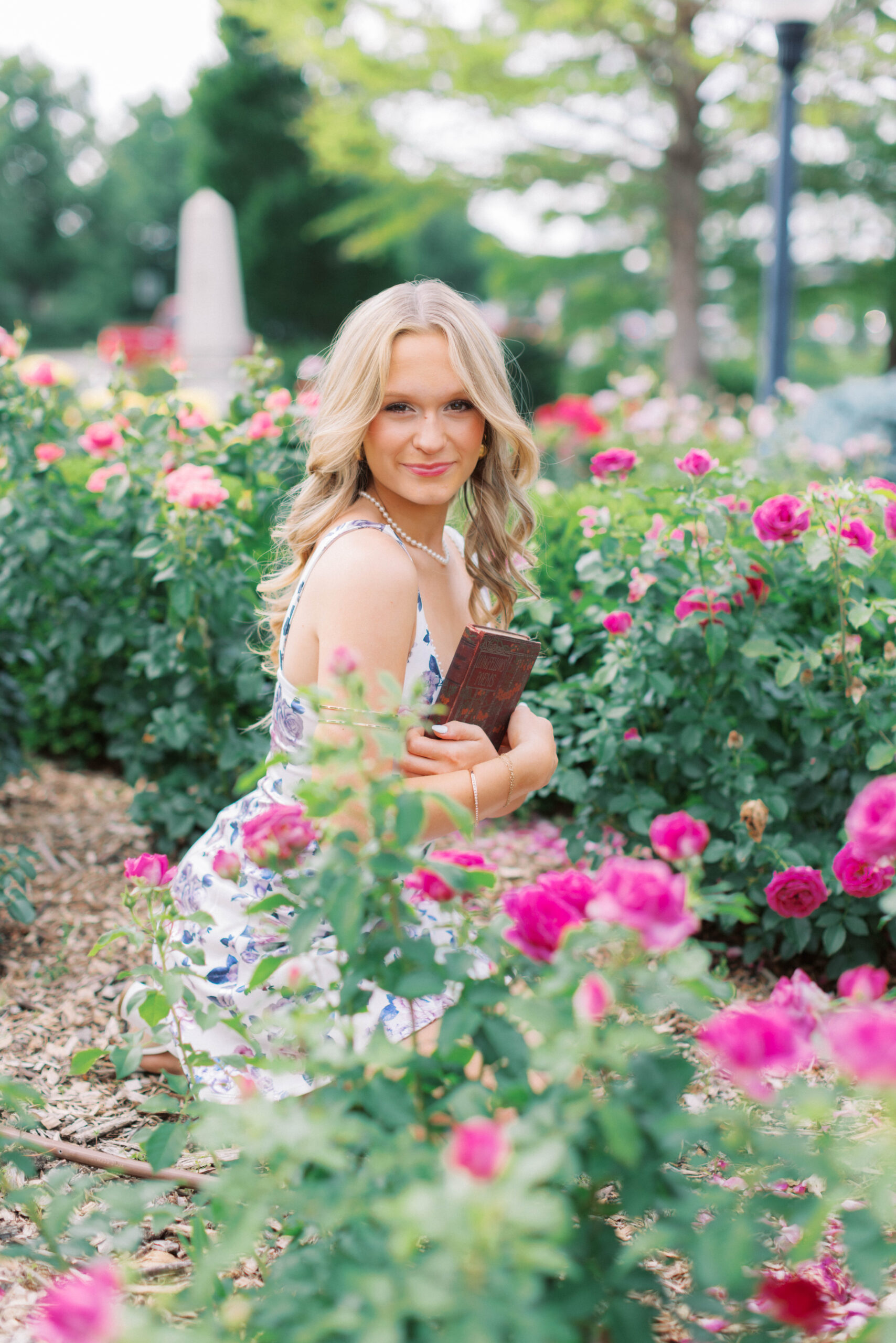 Senior girl in rose garden holding a book in Lincoln