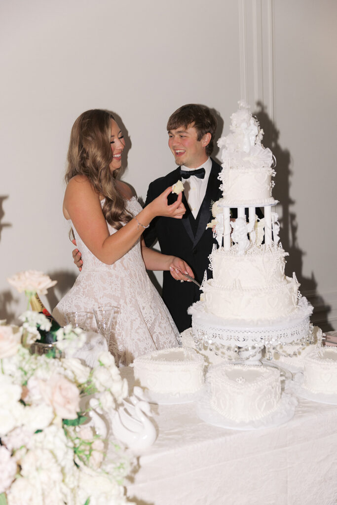 Bride and groom cutting a tiered white wedding cake at The Kimpton Cottonwood in Omaha