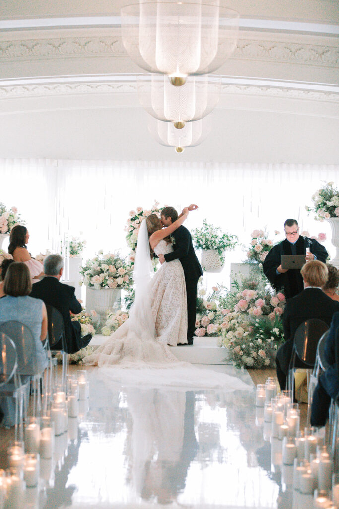 Bride and groom first kiss at the end of a candlelit aisle in the Schimmel Ballroom at The Kimpton Cottonwood