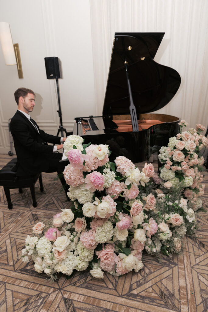 Live pianist at a grand piano surrounded by blush florals during dinner in the Gold Coast Ballroom