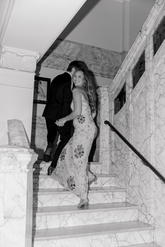 Black and white photo of the couple on a marble staircase during their Omaha wedding rehearsal weekend