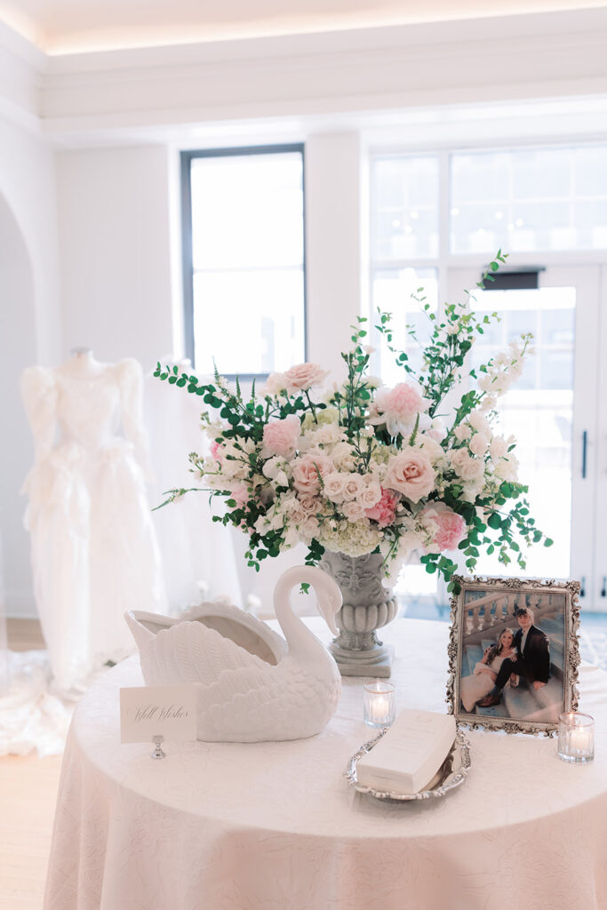 Swan vase, florals, and a framed family wedding photo on the welcome table at a Kimpton Cottonwood wedding