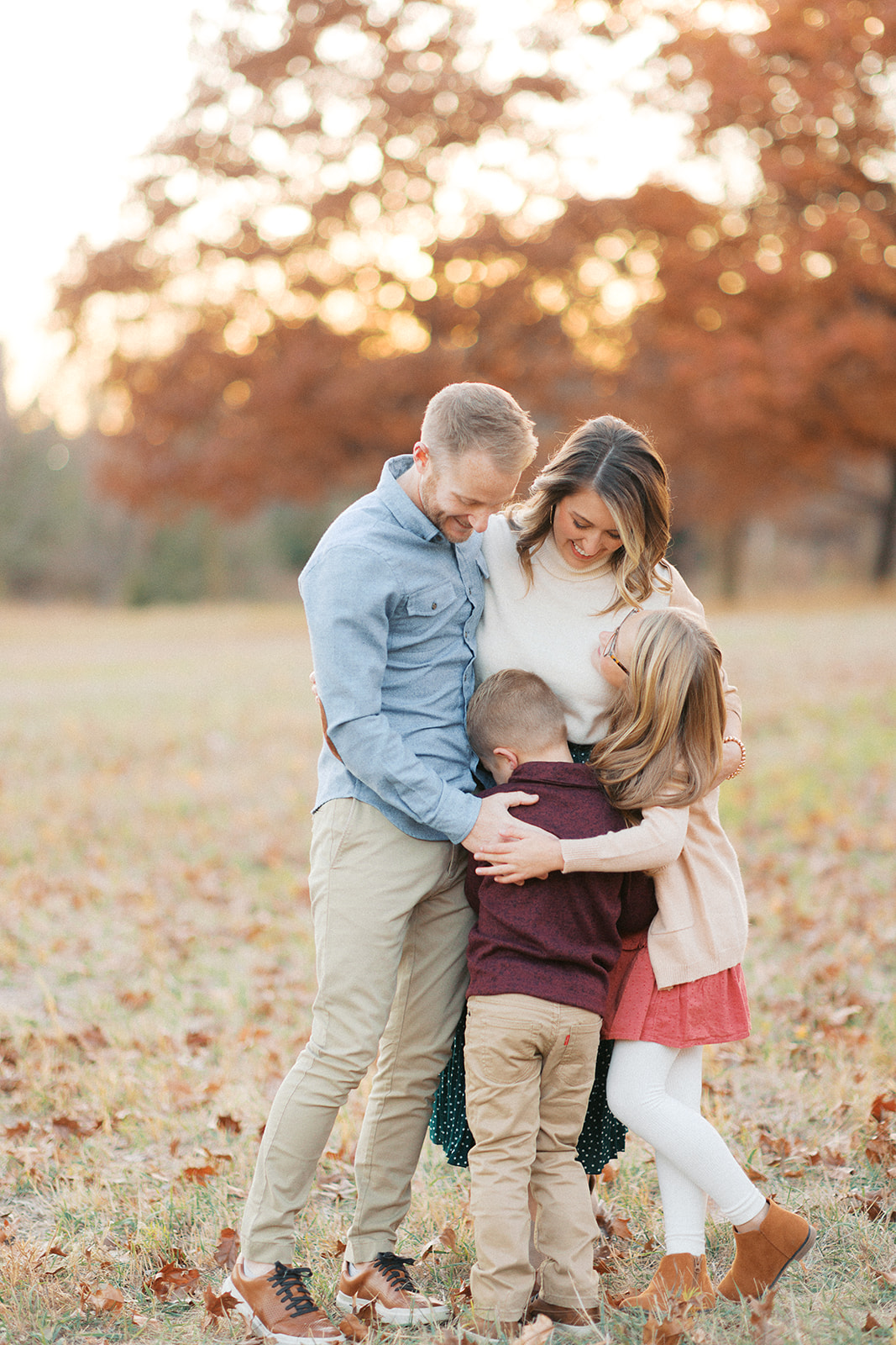 Mutchie family sharing a big group hug under peak fall color oak trees during a fall petite session in Lincoln, Nebraska
